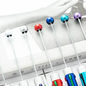 Bolígrafos retráctiles multicolores con varillas metálicas y cabezas esféricas decorativas.