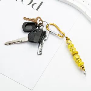 Creatieve DIY kraal karabijnhaak sleutelhanger met gele glasparels en metalen haak.