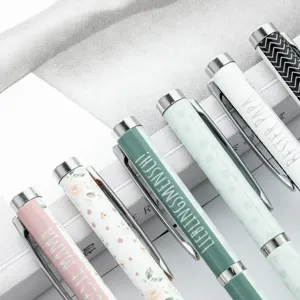 Assorted metal ballpoint pens with heat transfer print patterns and German text designs.