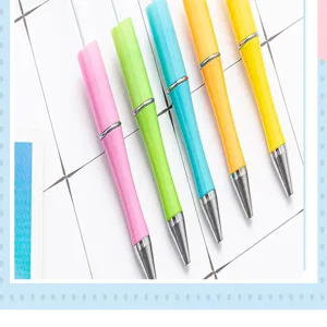 Colorful plastic ballpoint pens detail view, neat arrangement on grid paper for writing.