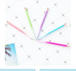 Vue détaillée de stylos à bille dégradés colorés disposés sur fond de grille blanche.