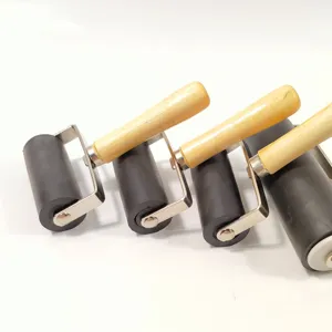 Detailweergave van rubberen drukrol met houten handvat en metalen beugel voor kunst.