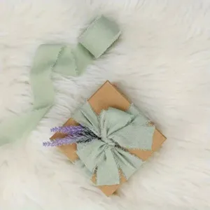 Nahaufnahme von hellgrünem Stoffband mit Fransenkanten auf Geschenkbox mit Lavendel.
