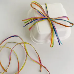 Corda di rafia colorata e scatola di carta bianca per confezioni regalo e decorazione dolci.