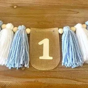 Banner decorazione festa primo compleanno con nappe filato blu bianche e perline in legno.