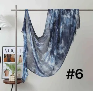 Detailed view of the blue tie-dye modal scarf hanging on a metal rack in a cozy studio.