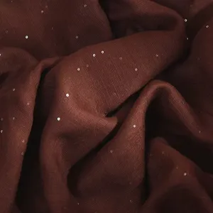 Close-up detail of dark brown shimmering sequin fabric shawl texture, soft and breathable.