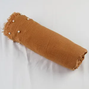 Detailed view of rolled camel cotton-linen scarf featuring elegant pearl decor and fringed ends.