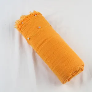 Detail shot of the yellow cotton linen scarf featuring delicate pearl beads and textured fringe.