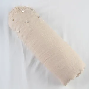 Beige linen scarf with pearl decor and frayed fringe edges, delicate detail view for women.