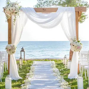 Outdoor wooden wedding arch with white sheer fabric drape for ceremony decoration beach party.