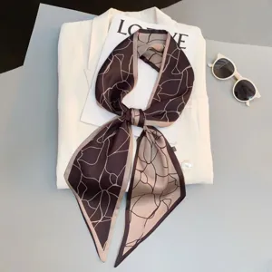 Detail view of a chic narrow twilly silk scarf with abstract linear print, styled for versatile use.