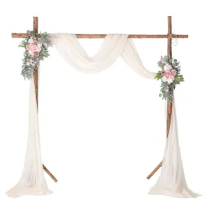 Wooden wedding arch decorated with artificial pink flowers and champagne chiffon fabric.