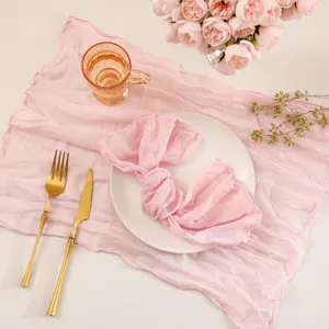 Detail view of pink gauze table runner and napkin staging with golden cutlery and flowers.