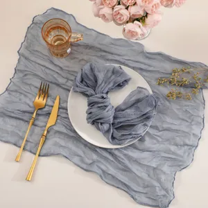 Blue cheesecloth table runner detail, soft textured gauze fabric for wedding party decor.