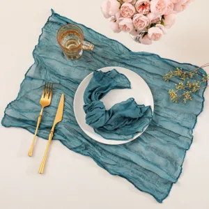 Close-up detail of textured teal cheesecloth table runner, perfect for wedding party decor.