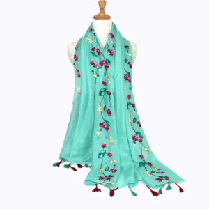 Turquoise cotton linen embroidered scarf detail showcasing vibrant floral patterns and elegant tassels.