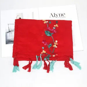 Detailed view of the red embroidered linen scarf with colorful floral patterns and tassels.
