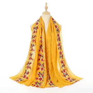Close-up of yellow cotton linen shawl with exquisite ethnic floral embroidery details.