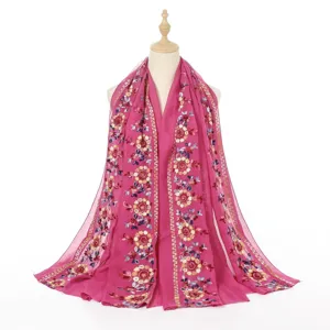 Detailed view of colorful floral embroidery on a vibrant pink cotton linen shawl scarf.
