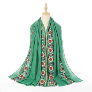Detailed close-up view of the green cotton linen shawl featuring exquisite floral embroidery.