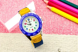 Detailaufnahme der Kinderuhr mit bunten Ziffern, blauer Bezel und süßem Smiley-Armband.