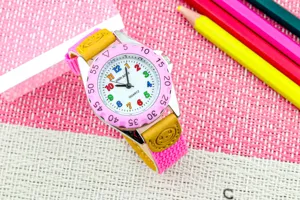 Detailansicht der Kinderuhr mit bunten Zahlen, rosa Lünette und bequemem Canvas-Armband.