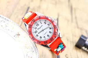 Gros plan détaillé du cadran de la montre pour enfants avec sa lunette rouge et son bracelet.