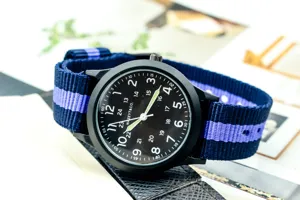 Detailed close-up shot of quartz military watch with blue nylon strap and black dial.