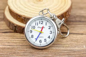 Gros plan d'une montre de poche à quartz avec chiffres arabes clairs et anneau de porte-clés.