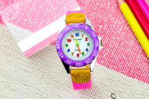Detailopname van kinder quartz horloge met kleurrijke wijzerplaat en roze band.