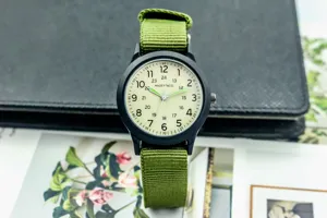 Gros plan du cadran d'une montre pour enfants avec boîtier noir et bracelet en nylon vert.