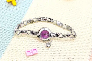 Vue détaillée de la montre quartz argentée avec bracelet cœur creux et cadran violet.