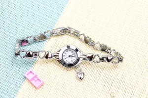 Gros plan détaillé de montre quartz femme argentée avec bracelet maillons cœur creux.