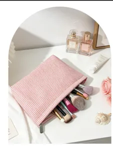 Detailed view of a stylish pink striped seersucker cosmetic bag filled with makeup brushes on desk.