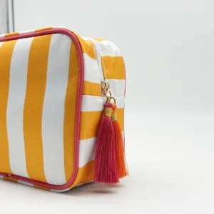 Detail shot of yellow white striped toiletry bag with vibrant pink and orange zipper tassels.