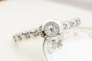 Vue détaillée montre quartz argentée femme avec bracelet chaîne cœur évidé et charm.
