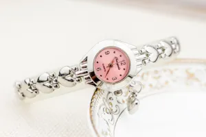 Montre quartz femme élégante avec cadran rose et bracelet cœurs ajourés, vue de détail.