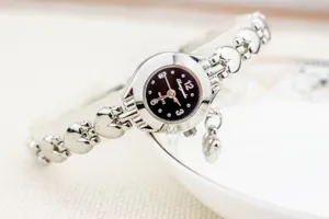 Détail d'une montre à quartz élégante à maillons en forme de cœur au design argenté.