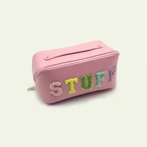 Detalle de neceser de cuero PU rosa con letras STUFF bordadas de colores y práctica asa.