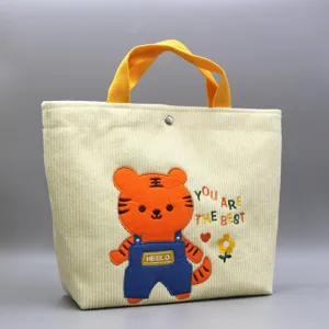 Detail de sac a main en velours cote avec broderie de tigre et poignees jaunes pratiques.