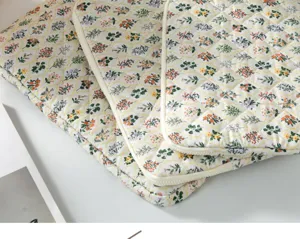 Close-up detail showing the delicate floral pattern and neat quilted texture of the laptop sleeve.