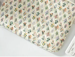 Quilted laptop sleeve detail with floral pattern on white fabric for 13-inch tablets.