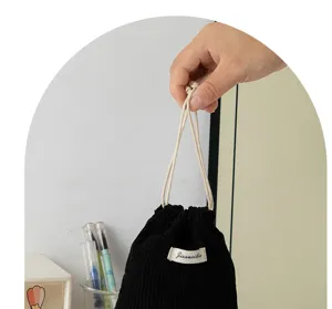 Black corduroy drawstring pouch detail, portable mini cosmetic storage bag with cute label.