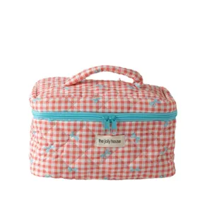 Cute quilted makeup bag with pink gingham pattern, blue bows, zipper, and handle.