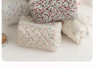 Dettaglio di borsa cosmetica trapuntata floreale, pochette da viaggio portatile con cerniera.