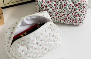 Dettaglio borsa cosmetica trapuntata a fiori, grande capacità e chiusura con zip.