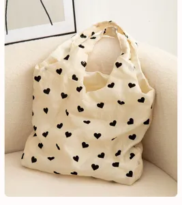 Beige tote bag with black hearts pattern, stylish fabric shoulder bag for daily casual use.