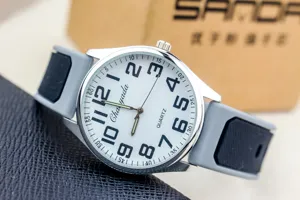 Detailed shot of a quartz watch with large arabic numerals and gray silicone strap.