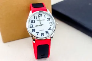 Detailed close-up of quartz watch with red and black silicone strap and clear dial.